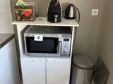 une petite cuisine équipée d'un micro-ondes, d'un réfrigérateur et d'une poubelle