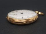 a close up of a gold pocket watch on a black surface