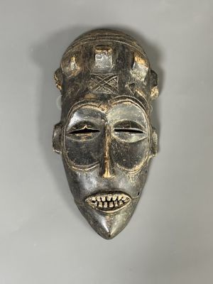 un gros plan d'un masque en bois accroché au mur