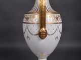 a white vase with a gold decoration on it