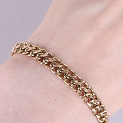 un gros plan sur la main d'une personne portant un bracelet à chaîne en or