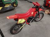 a small red dirt bike parked in a garage
