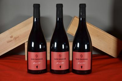 three bottles of red wine sit on a table next to a wooden box