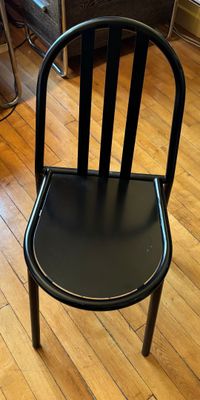 une chaise noire posée sur un parquet dans un salon