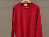 Le pull rouge est suspendu à un cintre devant un mur.