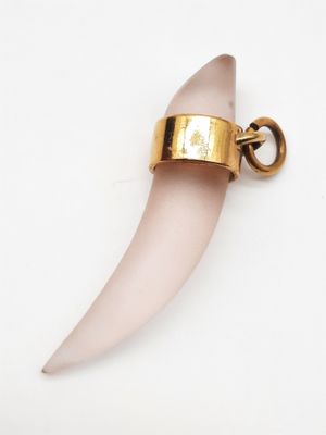 un gros plan d'un pendentif en pierre rose posé sur une surface blanche