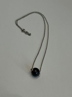 collier composé d'une perle noire montée sur une chaîne en argent, sur un fond blanc