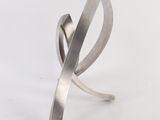 silver sculpture of a curved metal object on a white surface