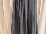 a grey skirt hanging on a hanger against a white curtain