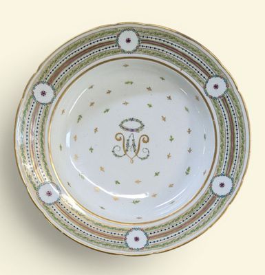 une assiette blanche bordée d'or et ornée d'un monogramme
