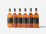 six bottles of whisky lined up on a white surface