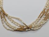 a close up of a necklace with pearls on a white surface