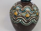 a brown vase with a green top on a white surface