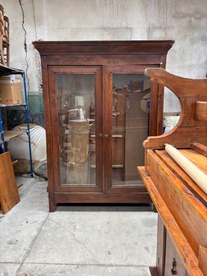 une armoire en bois avec une porte vitrée, à côté d'un piano