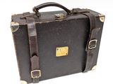 une valise marron posée sur une surface blanche