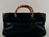 a black purse with a bamboo handle sitting on top of a table