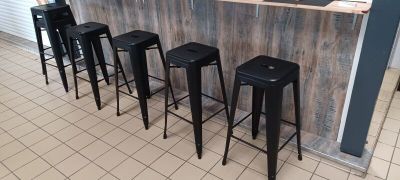 four black stools sitting in front of a counter