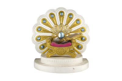 figurine de paon dorée et blanche posée sur un socle blanc orné de perles