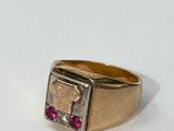 gros plan d'une bague en or avec une pierre rouge au centre
