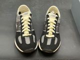 pair of black and white sneakers with yellow laces on a black surface
