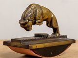 figurine en bronze représentant un taureau, posée sur un socle posé sur une table en bois
