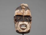 a close up of a wooden mask on a metal stand