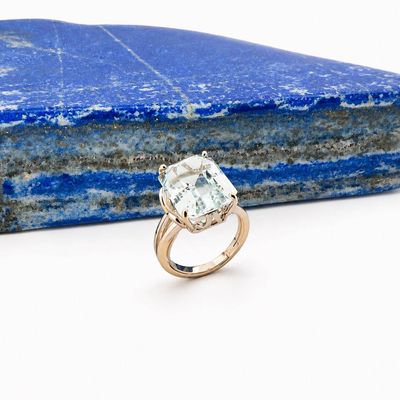 a close up of a diamond ring on a rock with a blue stone in the background