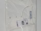 une chemise blanche emballée dans du plastique, posée sur une table