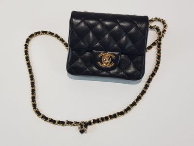 a black chanel bag with a gold chain on a white background