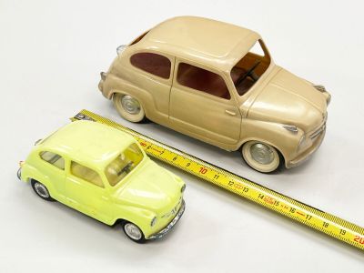 une petite voiture posée à côté d'une règle sur une surface blanche