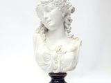 white bust of a woman with curly hair on a black and gold base