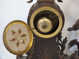 a clock that is sitting on a table with a bird on it