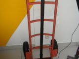 a red hand truck with a black handle next to a yellow and white wall