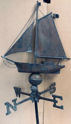 a metal weather vane with a sailboat on it
