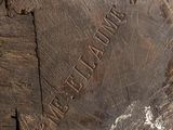 someone is holding a piece of wood with a carved inscription on it