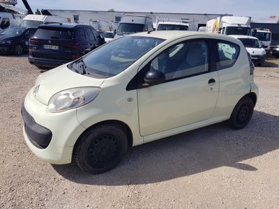 une petite voiture blanche garée sur un parking, avec d'autres voitures en arrière-plan