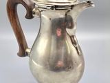 a silver coffee pot with a wooden handle sitting on top of a table