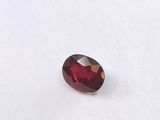a close up of a red garnet stone on a white surface