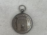 a small silver coin with a picture of a castle on it