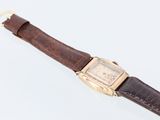 an image of a watch with a brown strap on a white surface