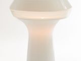 a white table lamp that is on a white surface