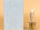 un flacon de parfum posé à côté d'une boîte de parfum sur une surface beige