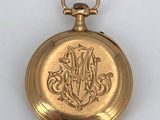 an image of a gold pocket watch with a monogram on the front