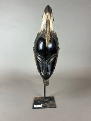 un gros plan d'un masque noir et doré posé sur un socle métallique
