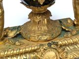 a gold and black vase on a stand with two cherns