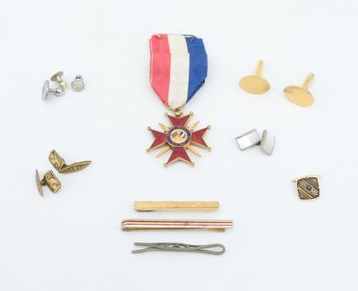 an image of a medal, pins, and a tie bar on a white surface