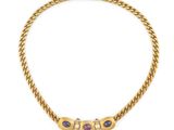 un collier en or avec trois pierres et une chaîne, sur fond blanc