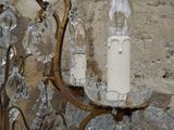 a chandelier with a candle on it hanging from a wall