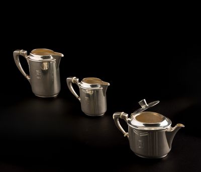 three pieces of silver teapots with lids on a black background