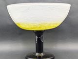 a yellow and white glass bowl on a black stand